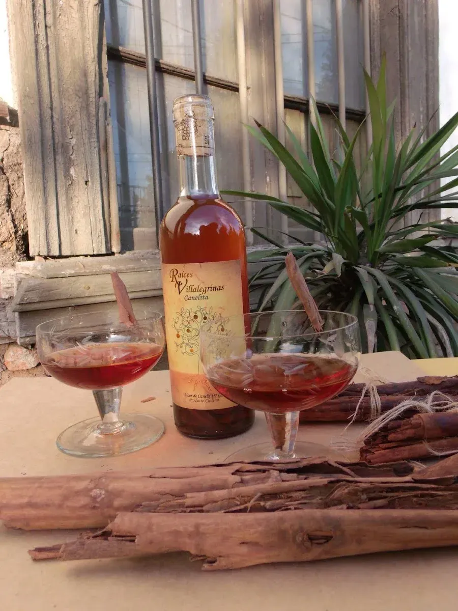 Botella de licor artesanal Canelita de Raíces Villalegrinas junto a copas servidas