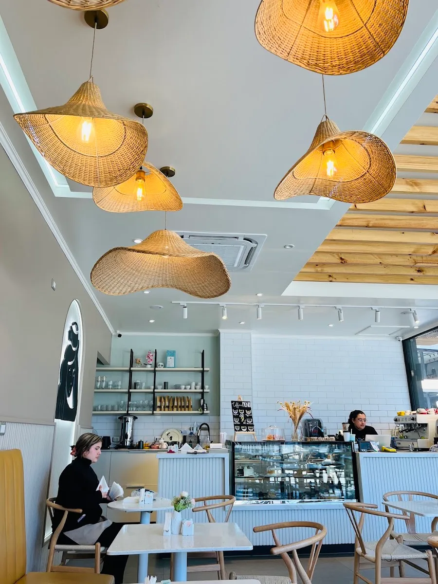 Salón de Ramona Café con lámparas de mimbre y mesas de madera