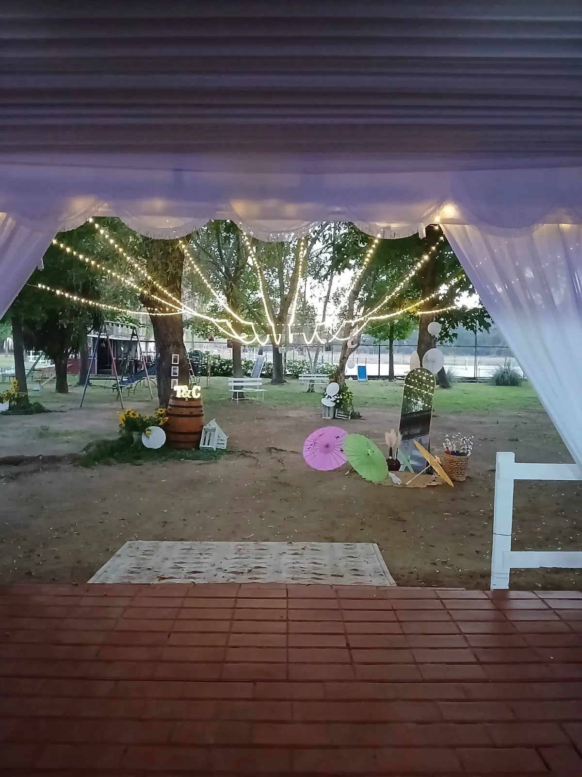 Montaje de ceremonia con cortinas blancas y luces bajo los árboles