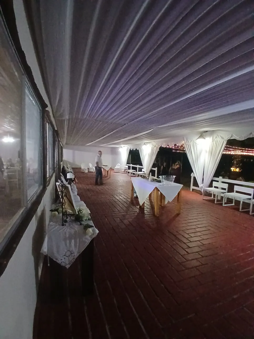 Terraza techada con cortinas blancas y piso de ladrillo