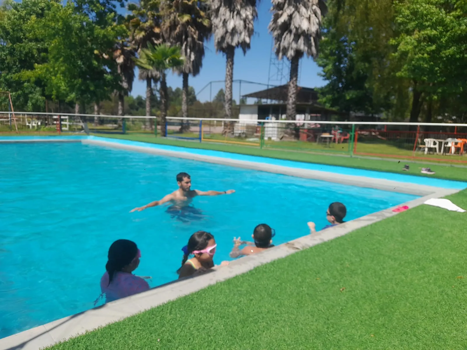 Adultos y niños bañándose en la piscina