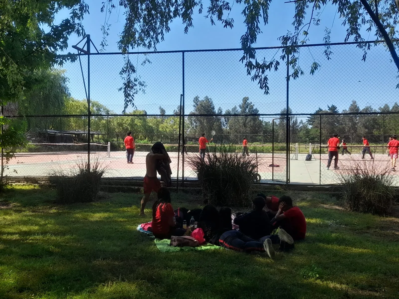 Paseo de curso: alumnos jugando en las canchas de tenis y descansando en el pasto
