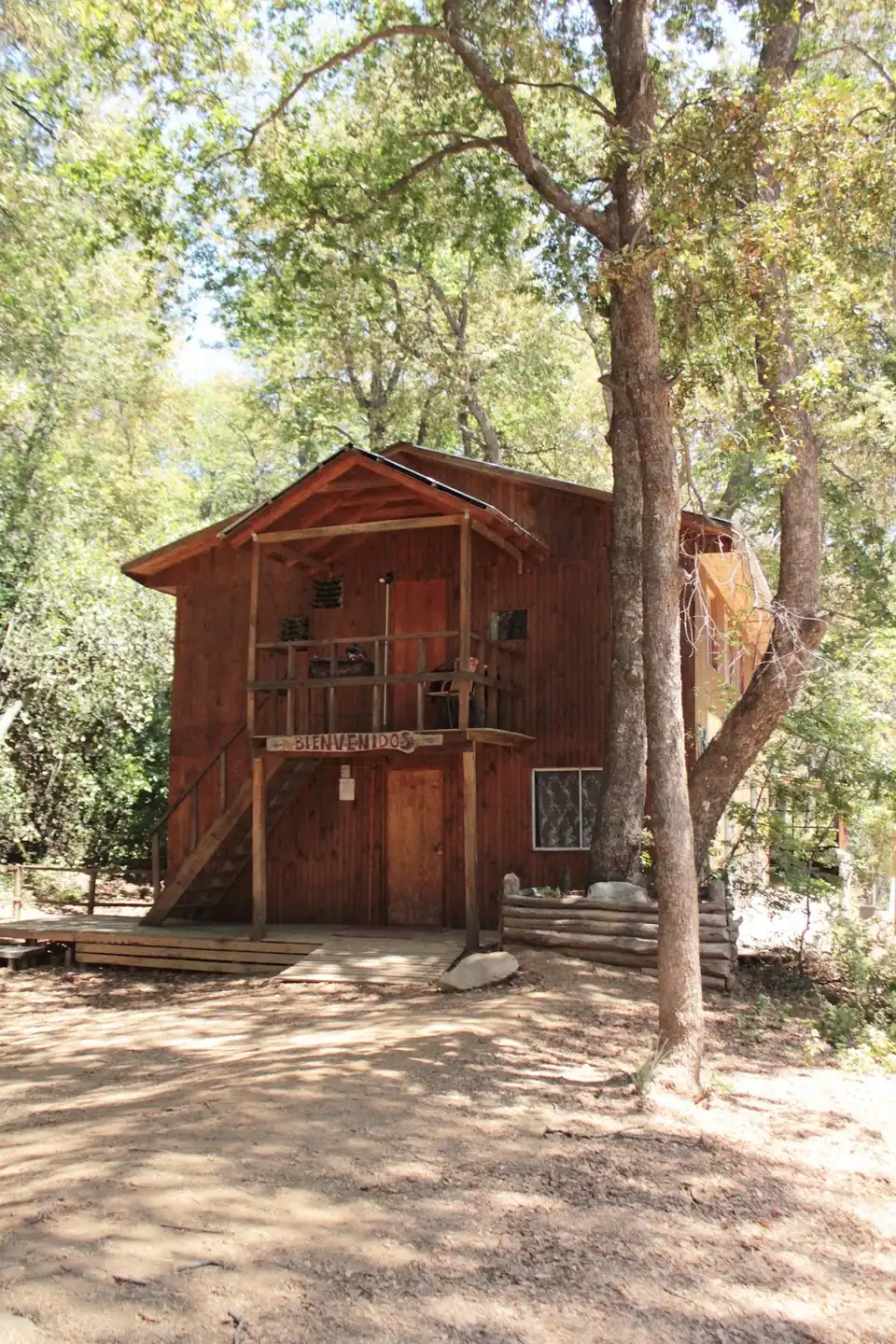 Cabaña de madera de El Rayadito entre robles, con letrero tallado Bienvenidos — foto real de su ficha de Google Maps