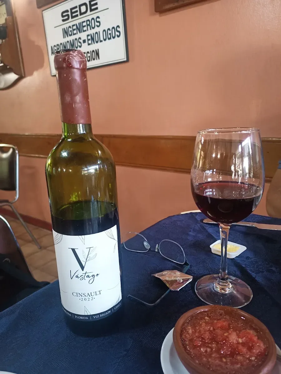 Botella de vino de la casa junto a una copa servida