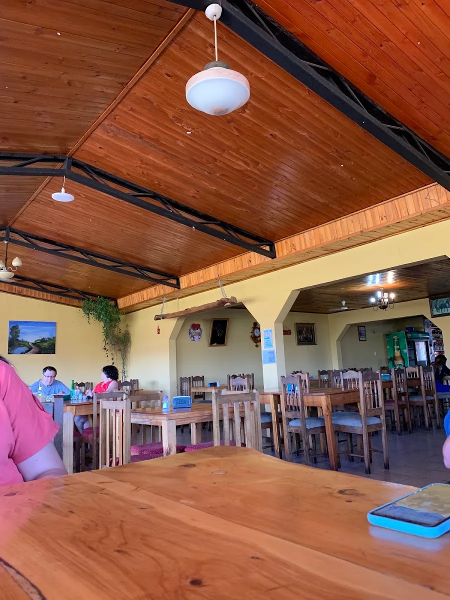 Salón interior de Donde Quelito con techo de madera, arcos y mesas