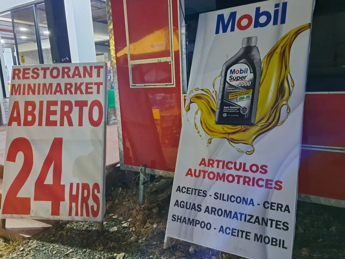 Letrero Restorant Minimarket Abierto 24 hrs junto al aviso de aceites Mobil