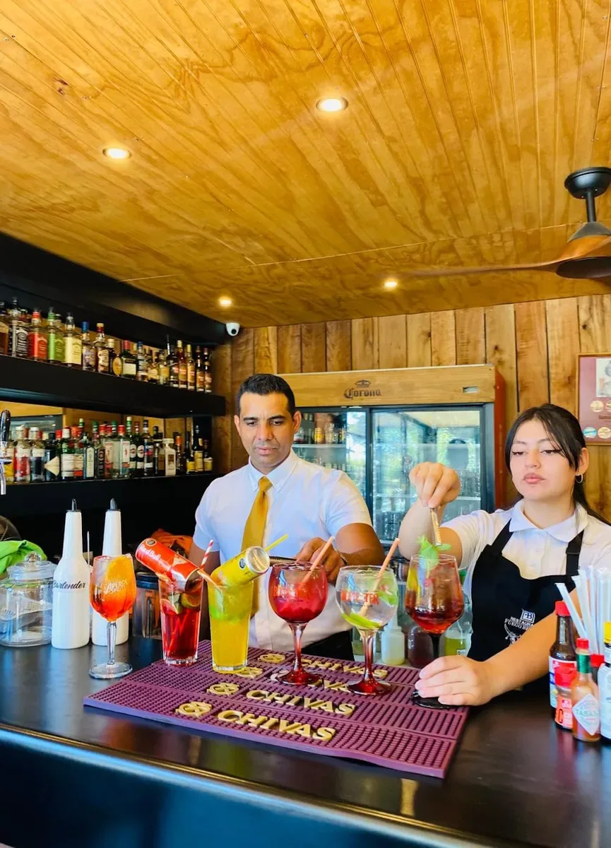 Bartenders preparando tragos de colores en la barra de Fuego Bendito