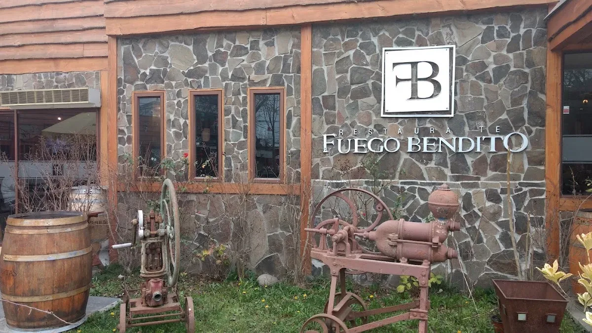 Muro de piedra laja con el letrero Fuego Bendito y carros antiguos