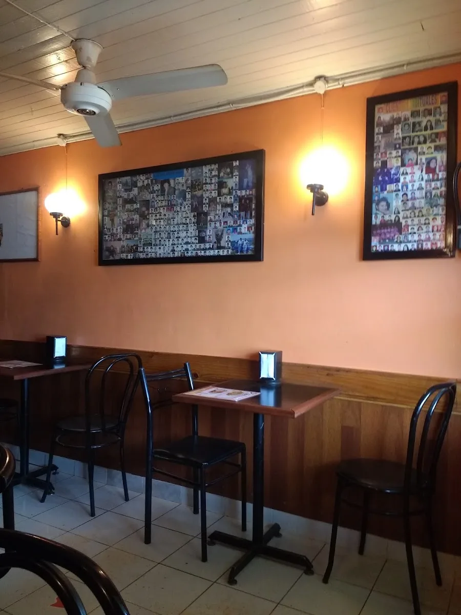 Comedor interior de La Rueda con paredes naranjas y collages de fotos de los clientes