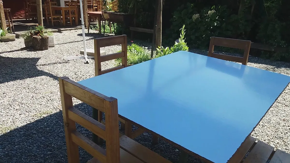 Mesa de la terraza del Pehuén rodeada de plantas y árboles del patio