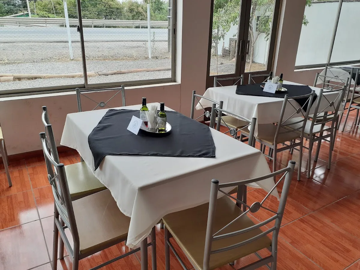 Comedor interior con mesas de mantel blanco y ventanales a la ruta