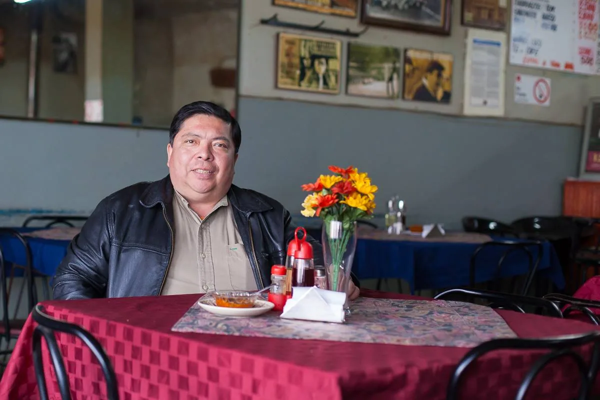 Interior del comedor de Tin Blan · Casa Meléndez, con sus dueños en la mesa del fondo y flores frescas