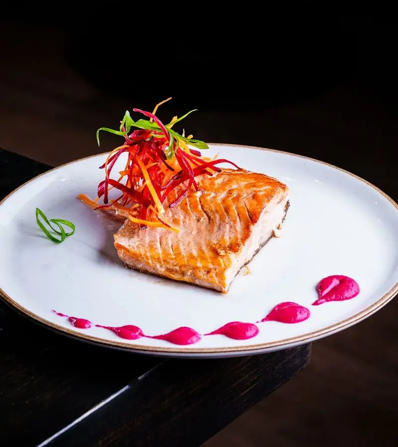 Filete de salmón con juliana de betarraga en plato blanco