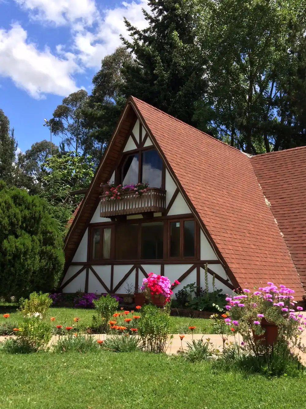Casa alpina del Restaurante Alemán Nueva Baviera con jardines y flores
