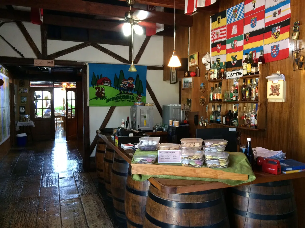 Interior de madera del restaurante con barra de barriles y banderas alemanas