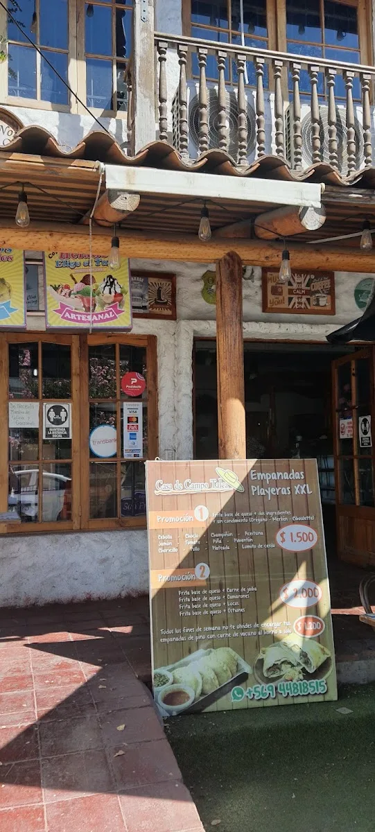 Entrada de la casona con pendón de empanadas playeras XXL y WhatsApp
