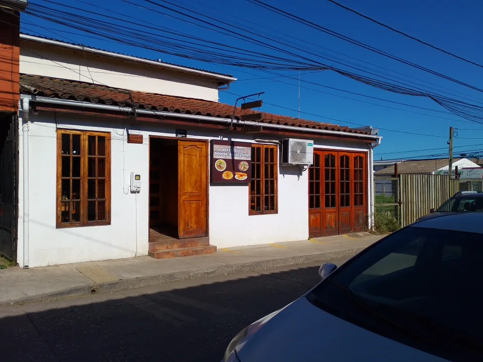 Fachada de Donde Raimundo: casa blanca con techo de teja y puerta de madera en Errázuriz, Chanco
