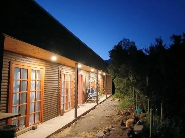 Pasillo techado de las cabañas de LEAN con puertas de madera, de noche