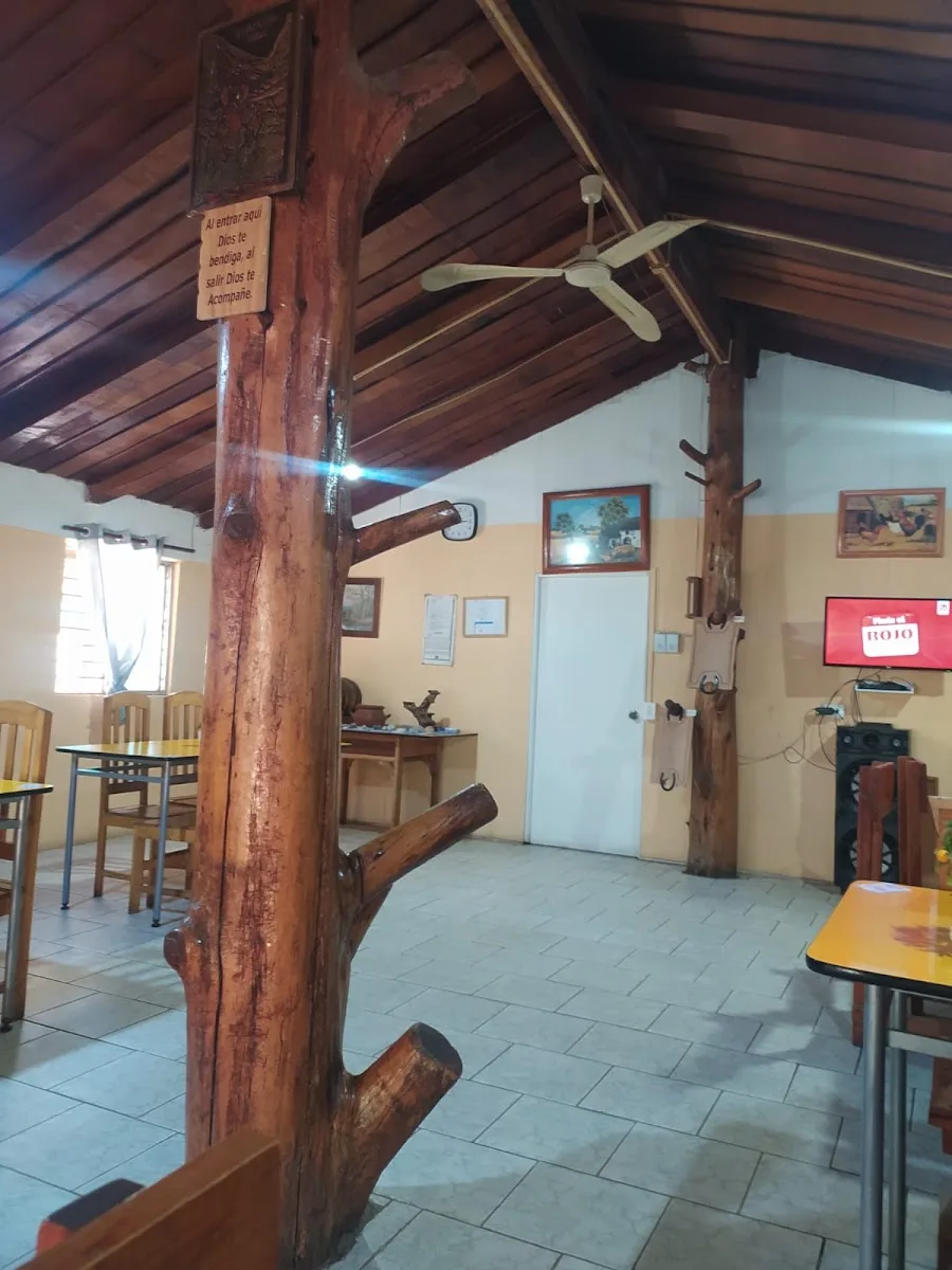 Comedor interior con pilares de tronco nativo, techumbre de madera y mesas