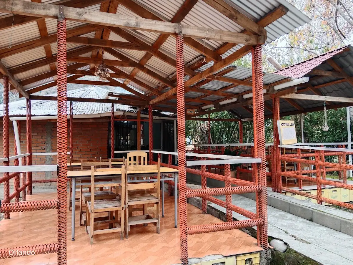 Quincho techado con estructura de madera y pilares pintados de rojo, con mesas