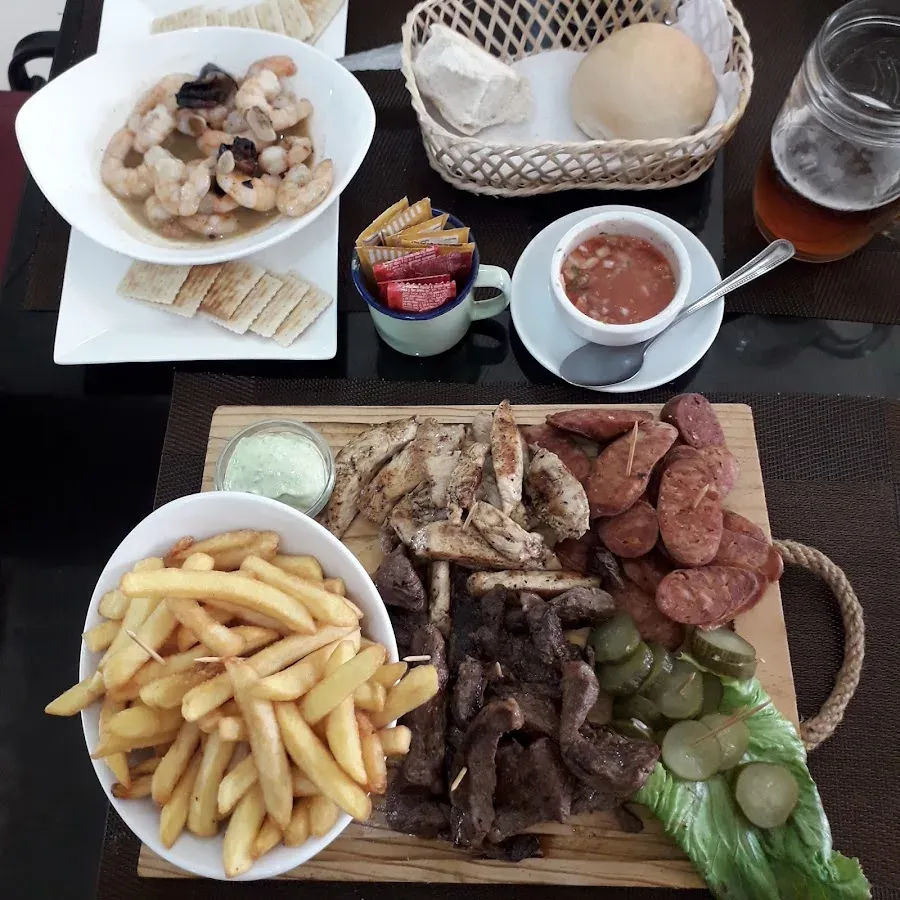 Mesa servida de Mar y Tierra: camarones al pil-pil, tabla de carnes con longaniza, papas fritas, pan y pebre