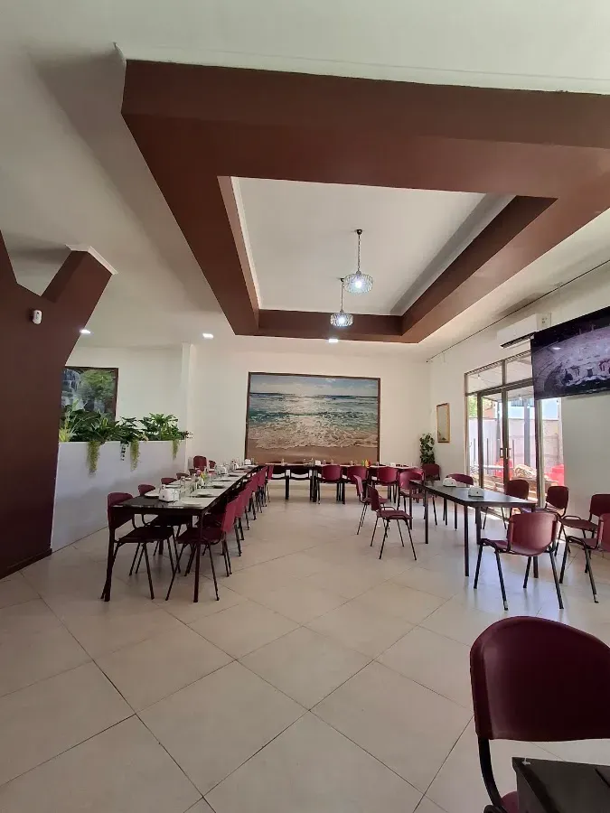 Comedor amplio de Mar y Tierra con mesas, sillas burdeo y un cuadro grande del mar