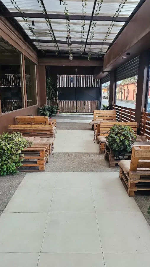 Terraza techada de madera con plantas y mesas rústicas