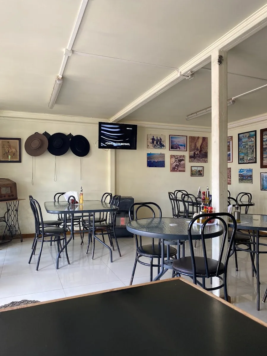 Salón del restaurante: mesas servidas, sombreros de campo colgados en la pared y cuadros