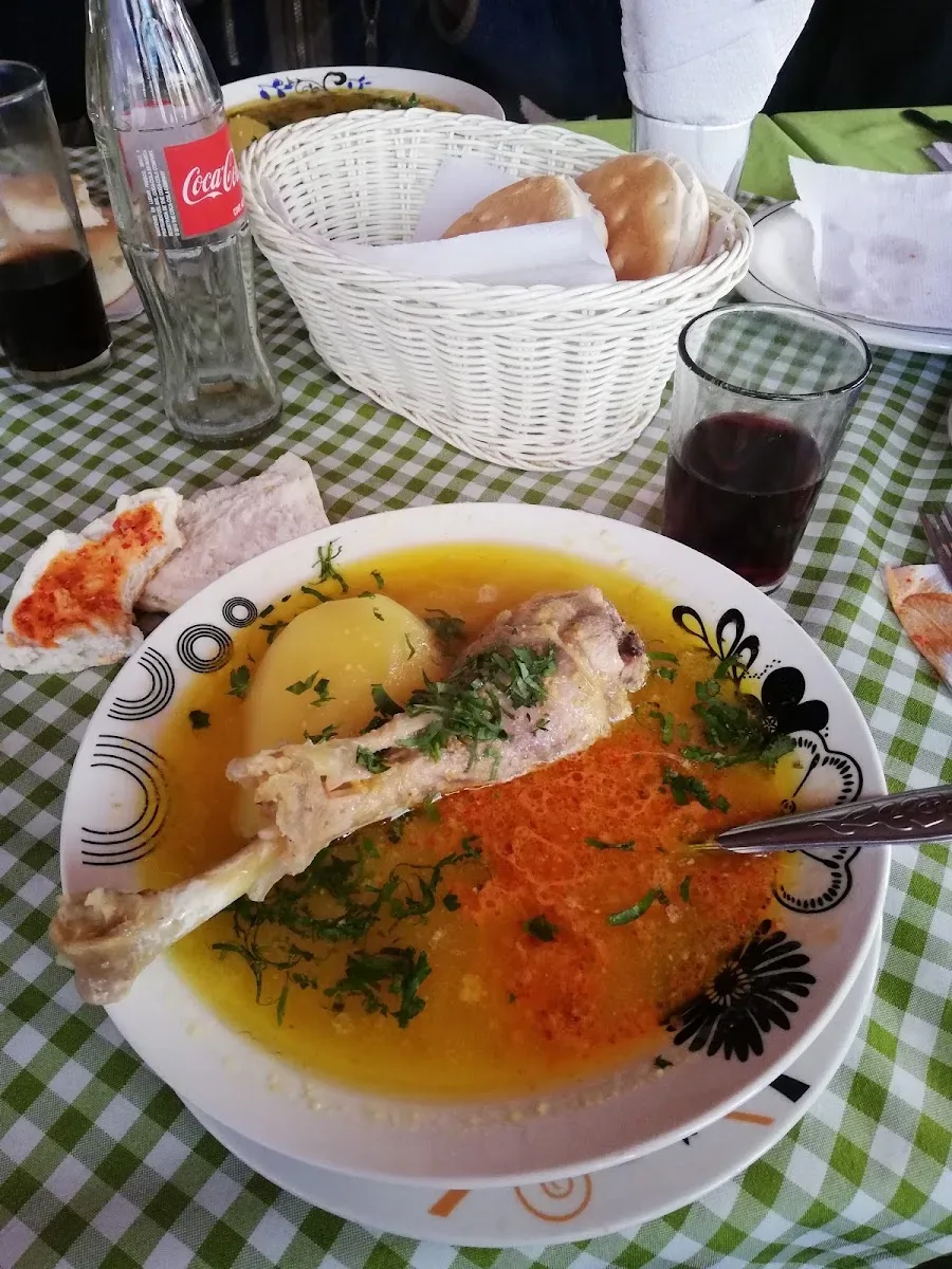 Cazuela servida con pan, copa y mantel de cuadrille en El Rucaray