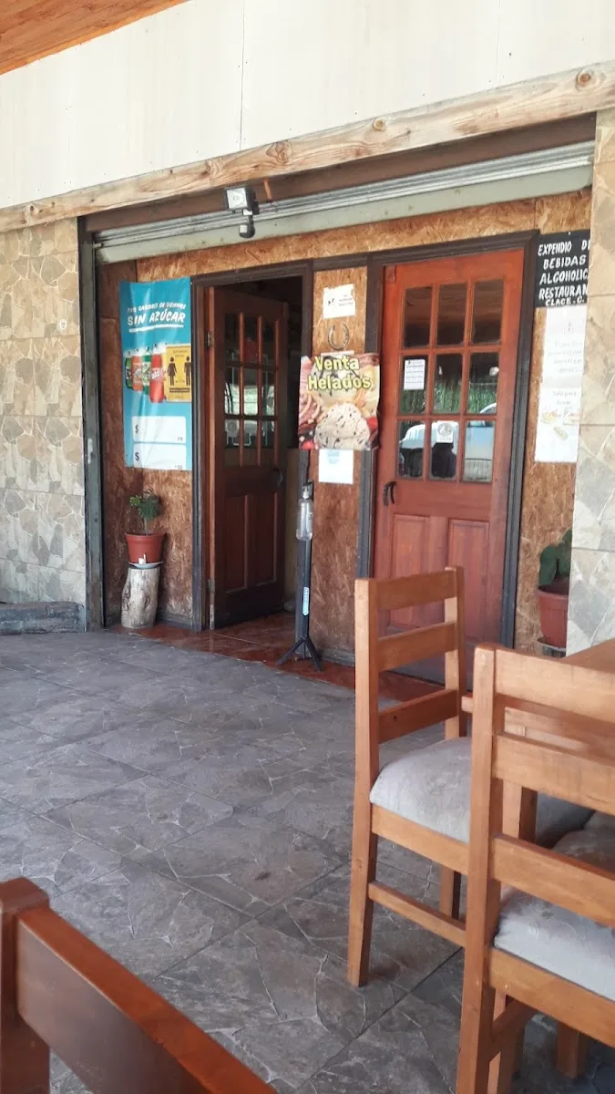 Fachada del restaurante: muro de piedra con puerta de madera roja y avisos en la entrada