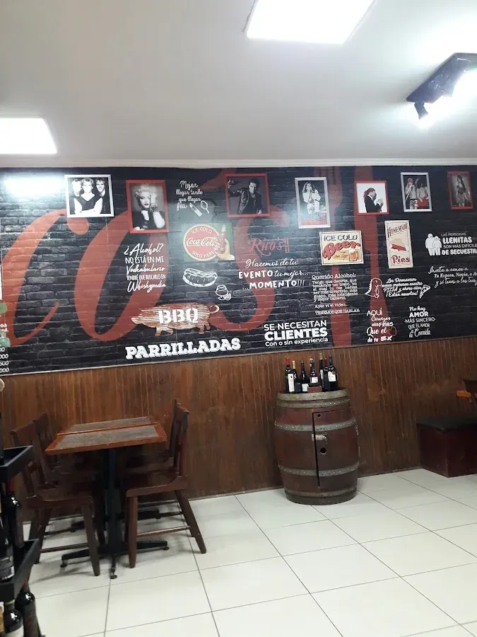 Mural interior de Rico's: el nombre en rojo gigante, el rótulo de parrilladas y afiches sobre ladrillo