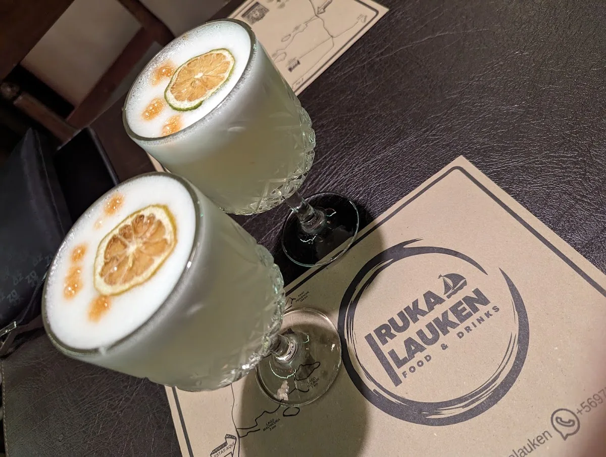 Pisco sour con rodaja de naranja sobre mantelito del local
