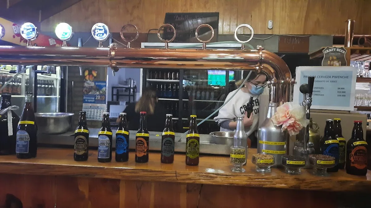 Barra de madera con torre de grifos de cobre y botellas Pwenche
