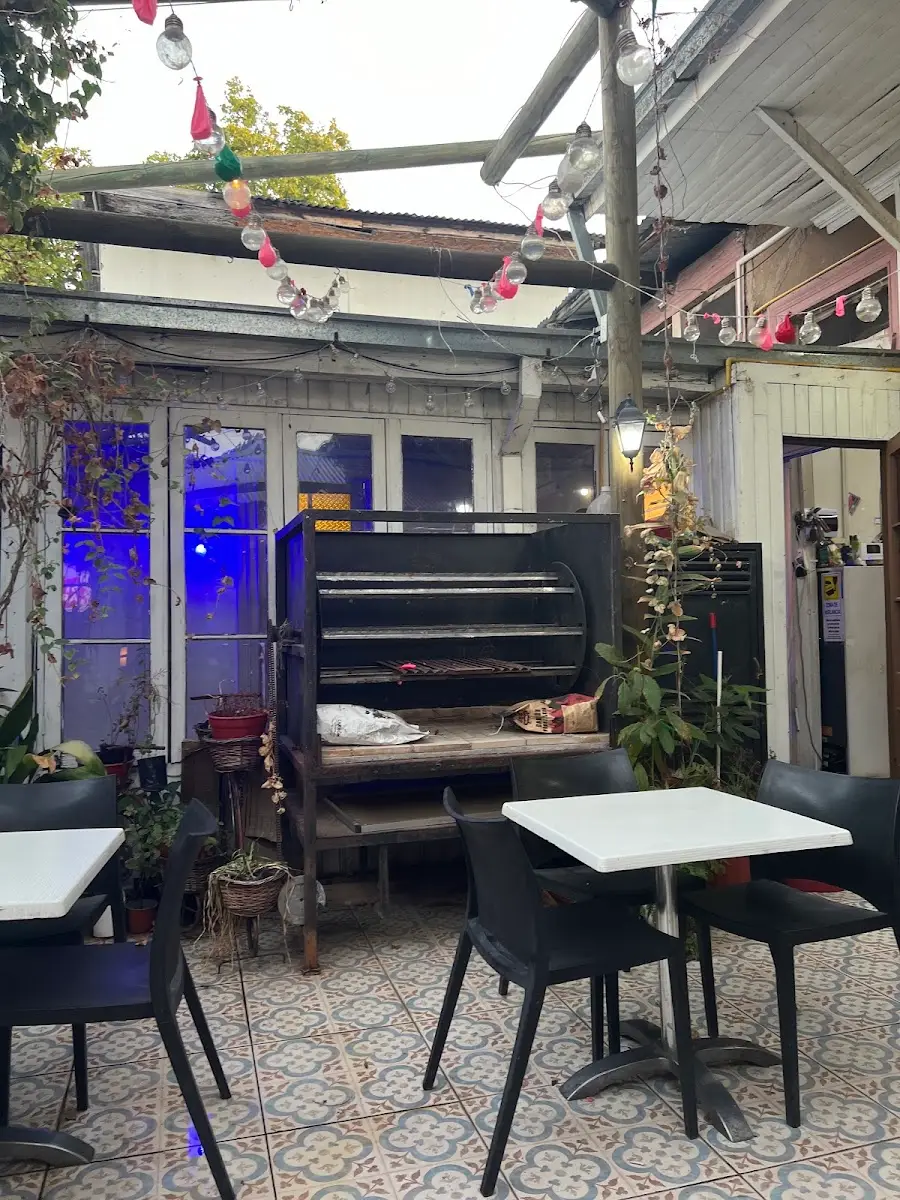 Terraza del taproom con mesas, parrilla y luces de feria