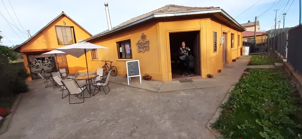 Terraza de Sabores Propios con mesas a la sombra frente a la fachada naranja