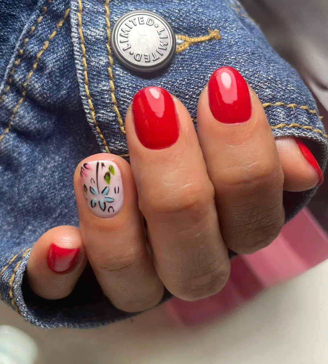 Manicure del salón en tono rojo con flor en acrílico