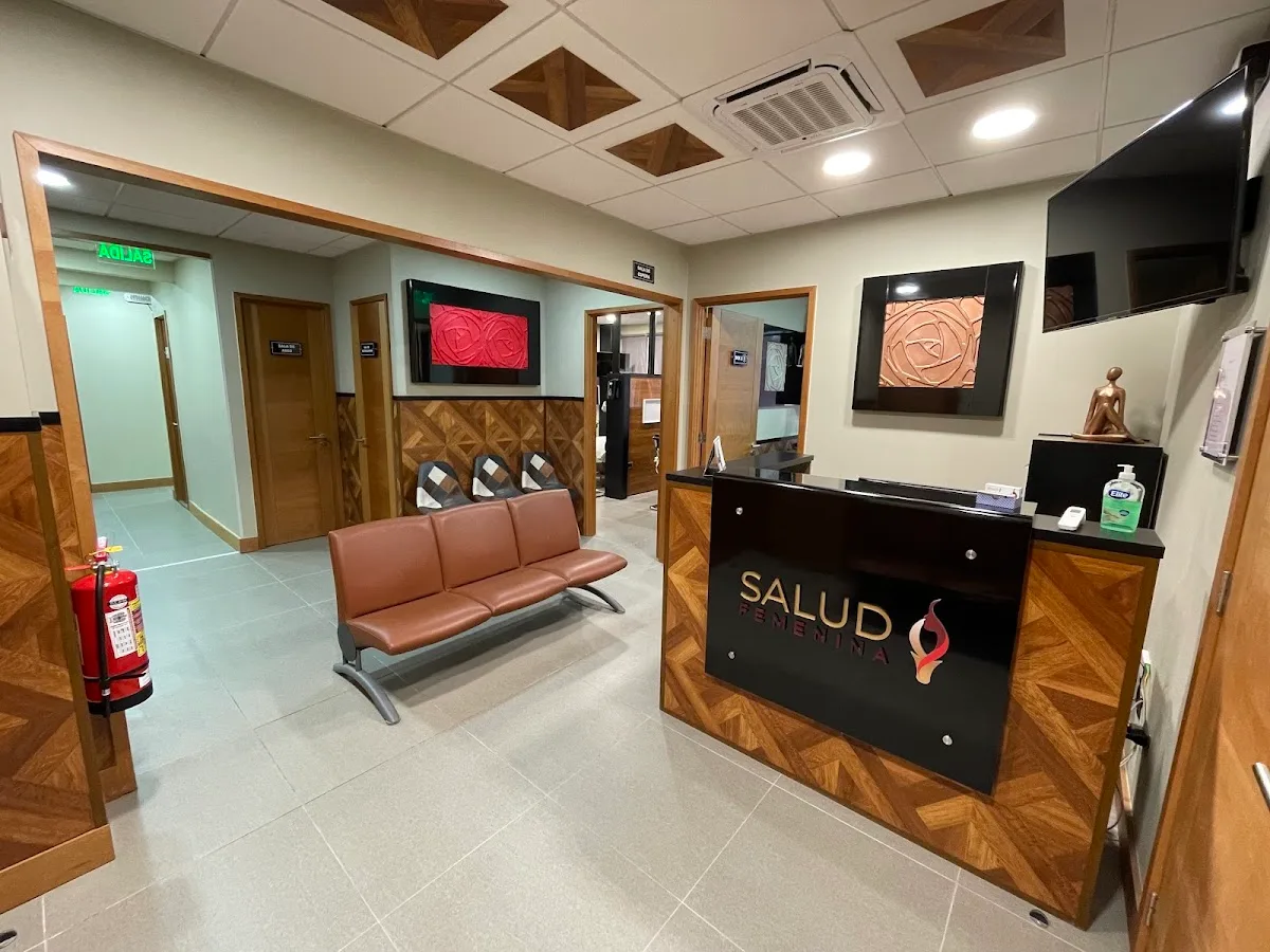 Recepción de Salud Femenina Talca: mesón negro con el logo en cobre, banqueta de cuero y madera geométrica