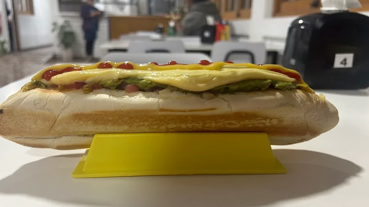 Completo con palta y tomate servido en soporte amarillo