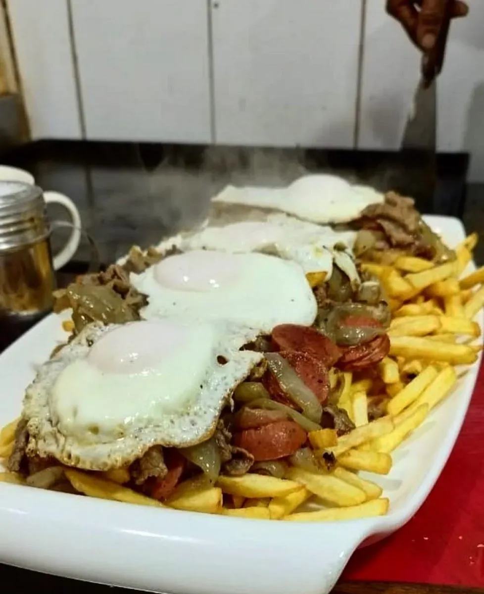 Plato de papas fritas con huevos fritos y carne