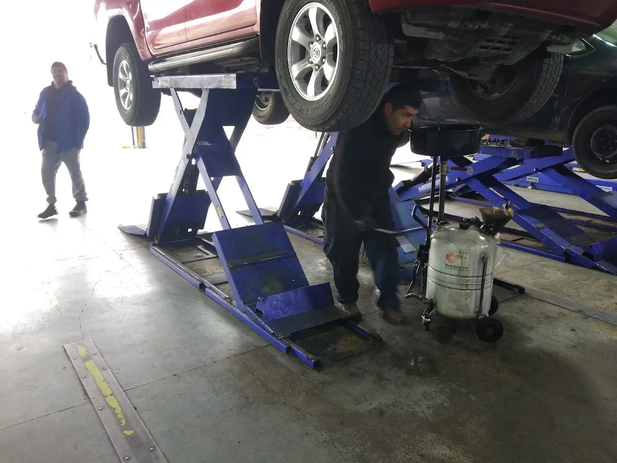 Mecánico trabajando bajo un auto en el elevador