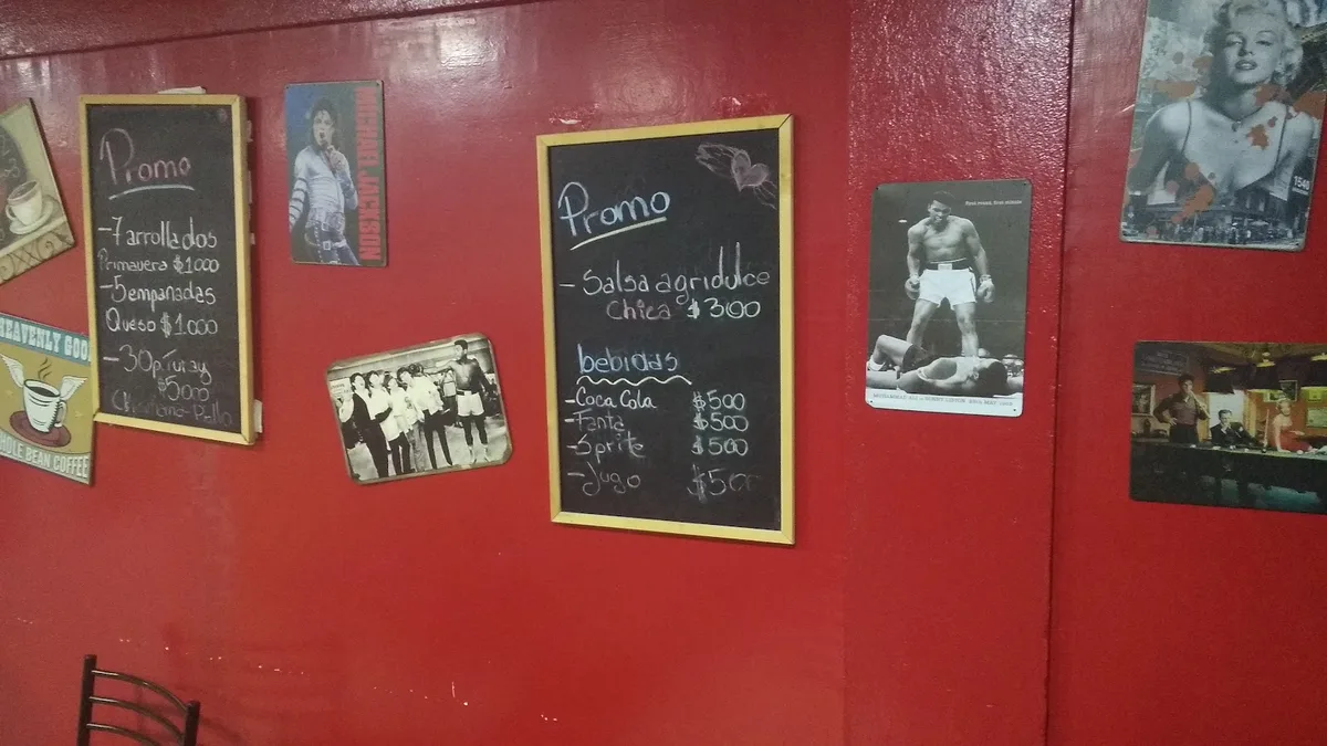 Muralla roja del local con las promociones escritas en pizarras