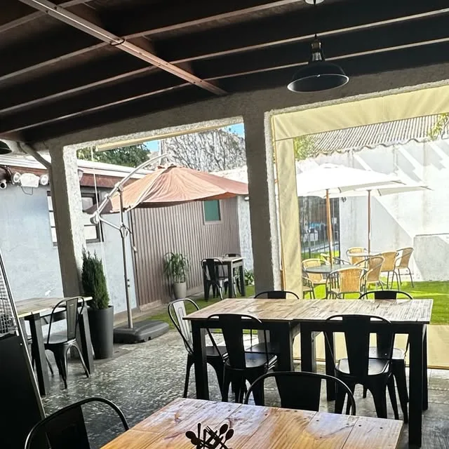 Terraza techada de Sushi Wey con mesas de madera y sillas negras