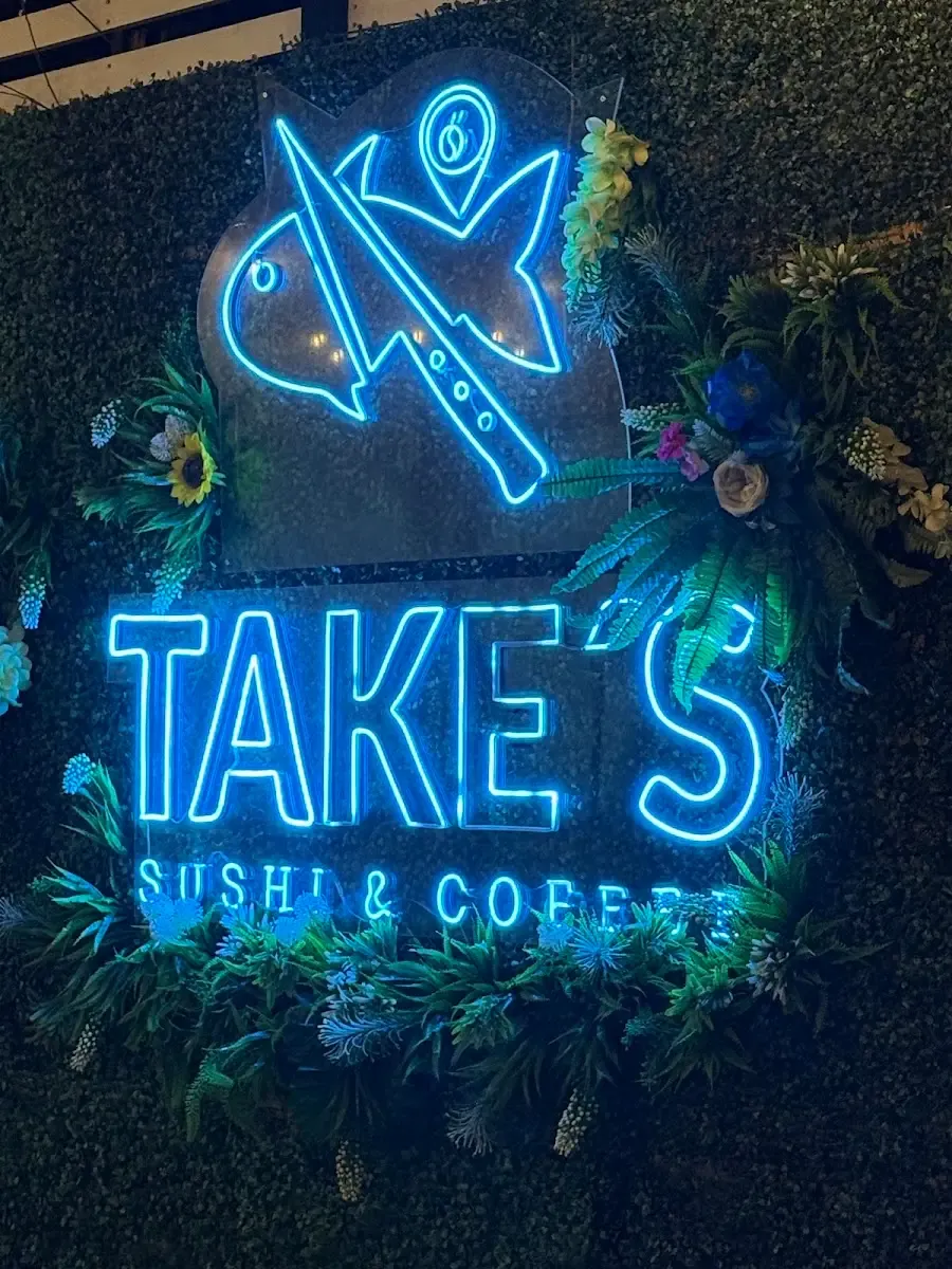 Letrero de neón de Take's Sushi & Coffee encendido en el interior del local
