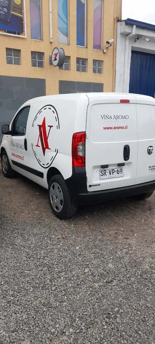Furgón blanco rotulado con logo rojo, visto desde atrás