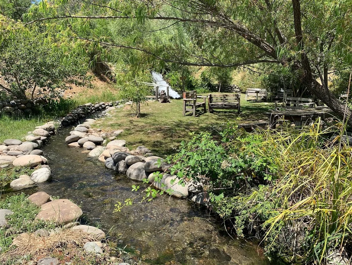 Laguna natural de Turismo Las Brujas en Colbún con visitantes y cerro al fondo
