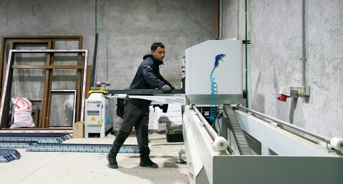 Operario de INVERLUM cortando perfiles de aluminio en sierra CNC dentro del taller