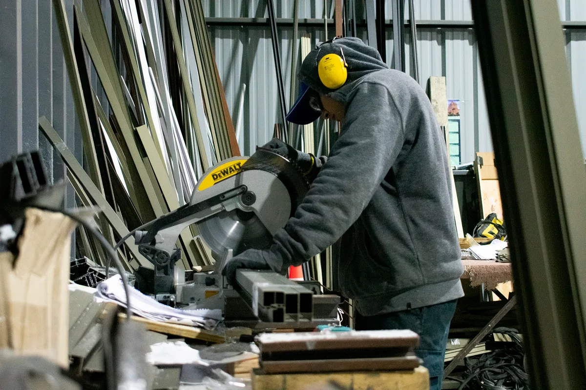 Trabajador cortando un perfil de aluminio en sierra ingletadora en el taller de INVERLUM