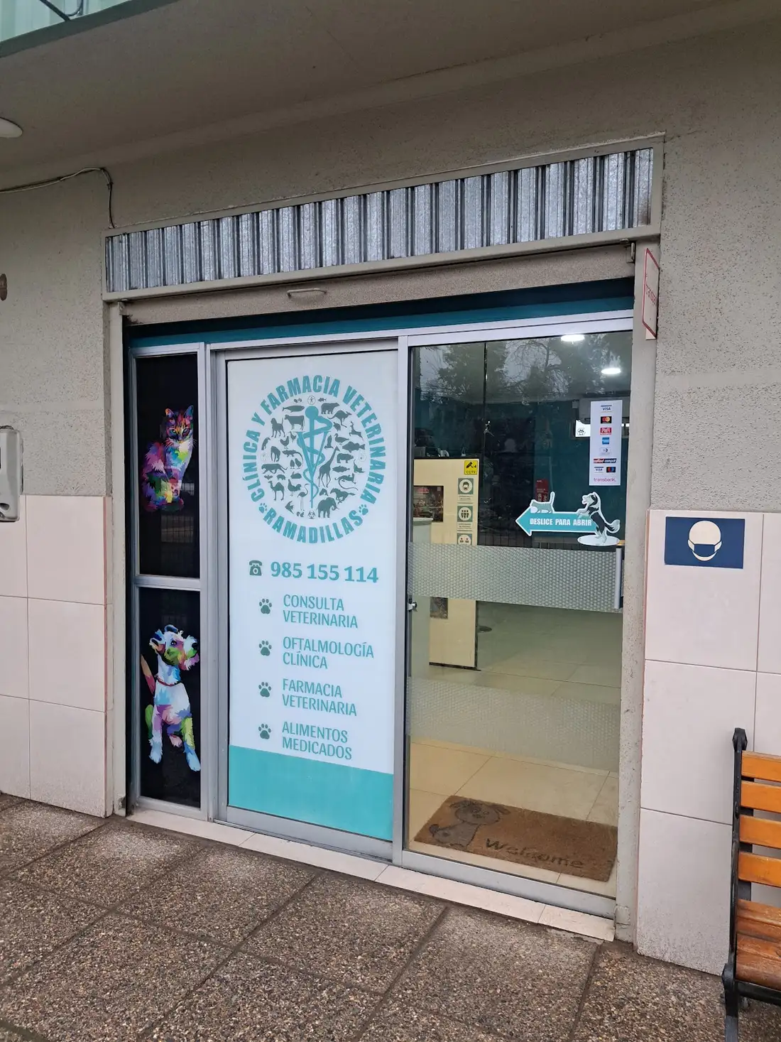 Puerta de vidrio de la Veterinaria Ramadillas con su logo turquesa y los servicios: consulta, oftalmología, farmacia y alimentos medicados