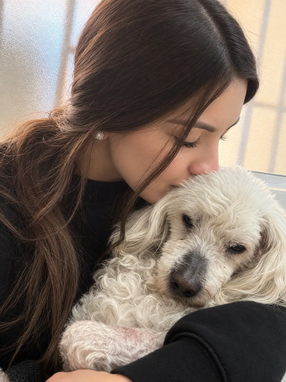 Integrante del equipo de SOS abrazando a una perrita blanca