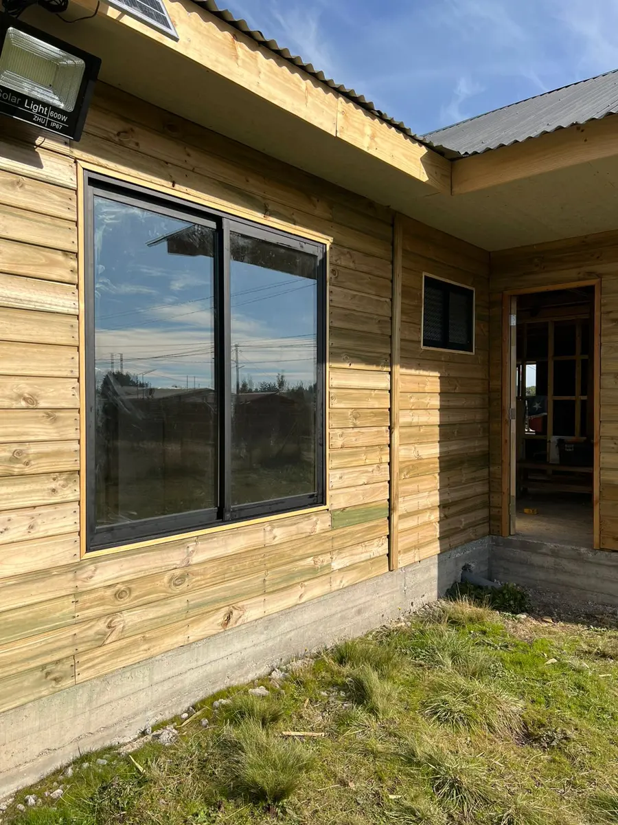 Casa de madera con ventanas de aluminio oscuras instaladas